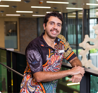 A man wearing a colorful shirt stands inside a building, surrounded by architectural features.